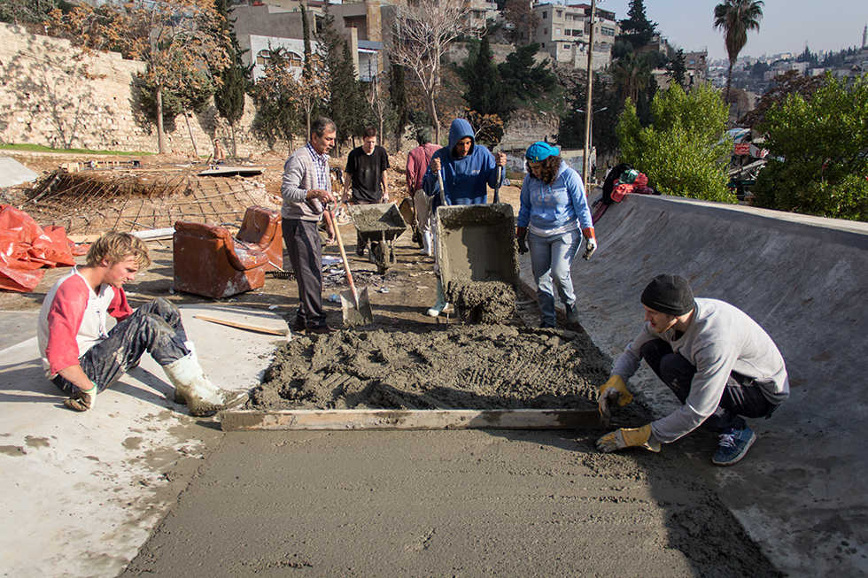 Volunteers work on leveling concrete floors in the central skating pool.