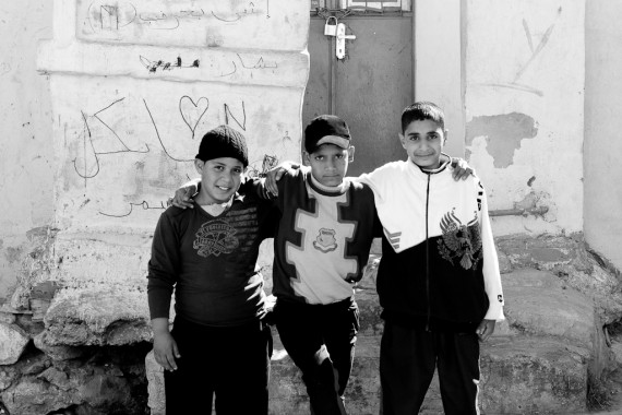 Three kids pose for the camera in front of their house in Jabal Amman