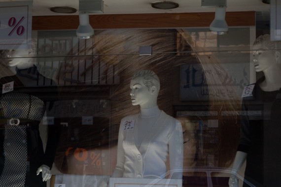 three mannequins standing in a shop window that offers 50 percent discount on all clothes